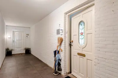 a hallway with umbrellas leaning against a white brick wall at Apartment Garden & Bed in Zandvoort