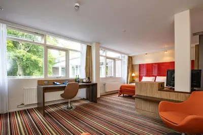 a hotel room with a desk and a bed at Fletcher Hotel Restaurant Amersfoort in Amersfoort