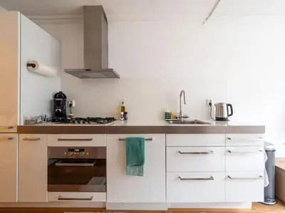 a kitchen with white cabinets and a sink and a stove at Riverbridge Suite - Historic Center Canal District in Amsterdam