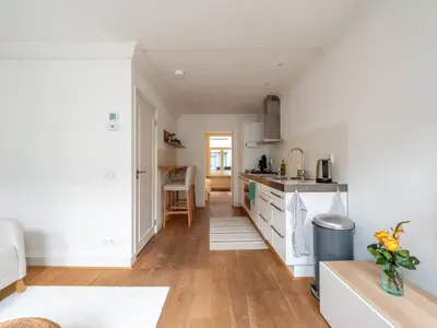 a kitchen with white cabinets and wooden floors at Riverbridge Suite - Historic Center Canal District in Amsterdam