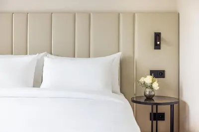 a bed with white sheets and a vase with flowers on a table at NH Amsterdam Leidseplein in Amsterdam
