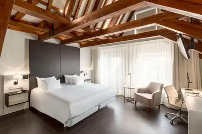 a bedroom with a large white bed and a chair at NH Collection Amsterdam Barbizon Palace in Amsterdam