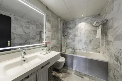 a bathroom with a sink and a tub and a toilet at NH Collection Amsterdam Barbizon Palace in Amsterdam