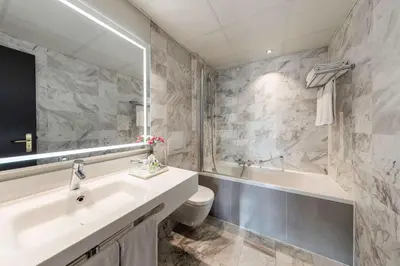 a bathroom with a sink and a tub and a toilet at NH Collection Amsterdam Barbizon Palace in Amsterdam
