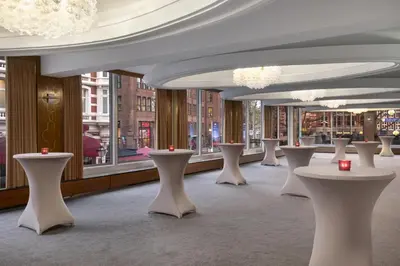 a row of tables in a room with windows at NH Amsterdam Caransa in Amsterdam