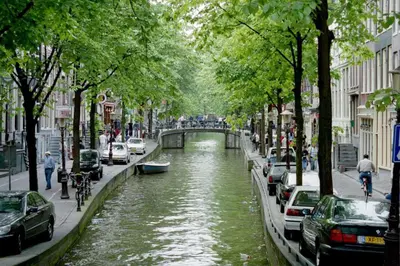 a canal in a city with cars and people on the street at NH Amsterdam Caransa in Amsterdam