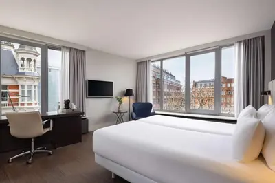 a hotel room with a bed and a desk and window at NH Amsterdam Caransa in Amsterdam