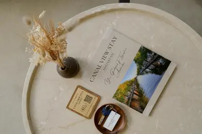 a table with a book and a card and a bottle at Canal View Stay Amsterdam in Amsterdam