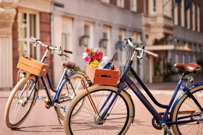two bikes parked on a street with flowers in a basket at Tivoli Doelen Amsterdam Hotel in Amsterdam