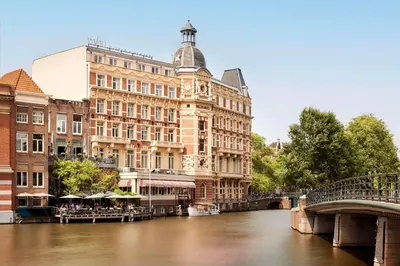 a building next to a river with a bridge at Tivoli Doelen Amsterdam Hotel in Amsterdam