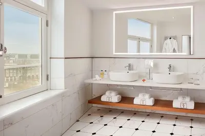 a bathroom with two sinks and a mirror at Tivoli Doelen Amsterdam Hotel in Amsterdam