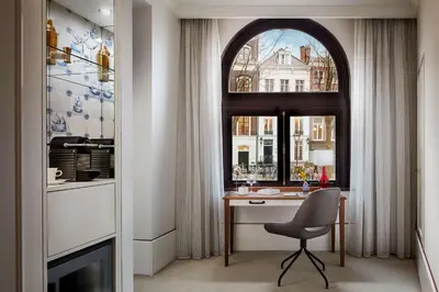 a room with a desk and a window with a chair at Tivoli Doelen Amsterdam Hotel in Amsterdam