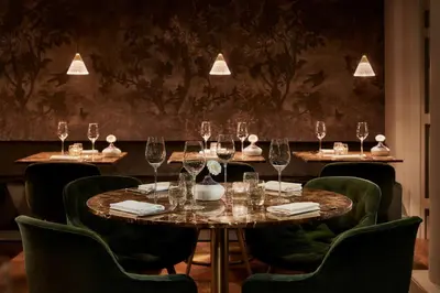 a set of tables in a restaurant with wine glasses at Tivoli Doelen Amsterdam Hotel in Amsterdam
