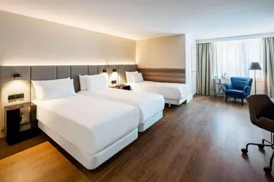 a hotel room with two beds and a chair at NH Amsterdam Schiller in Amsterdam