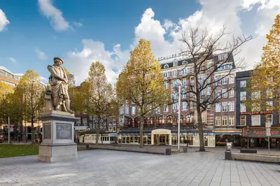 a statue of a man standing in a plaza in front of a building at NH Amsterdam Schiller in Amsterdam