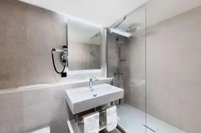 a bathroom with a sink and a shower and a mirror at NH Amsterdam Schiller in Amsterdam