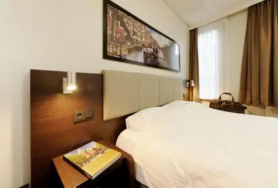 a hotel room with a bed and a table with a book at Best Western Dam Square Inn in Amsterdam