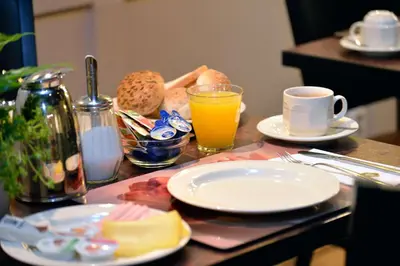 a table with plates of food and a cup of orange juice at Best Western Dam Square Inn in Amsterdam