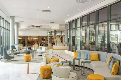 a lobby with couches and tables and windows at NH Amsterdam Schiphol Airport in Hoofddorp