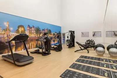 a gym with exercise equipment and a wall mural at NH Amsterdam Schiphol Airport in Hoofddorp