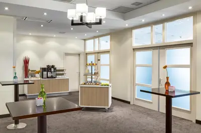 a room with two tables and windows at NH Bussum Jan Tabak in Bussum