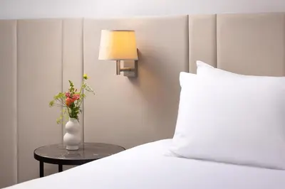 a vase with flowers on a table next to a bed at NH Bussum Jan Tabak in Bussum