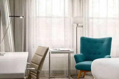 a room with a blue chair and a table and a lamp at NH Bussum Jan Tabak in Bussum