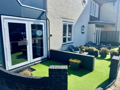 a garden with grass and plants in front of a house at Glücklich am Meer Suite Deluxe mit Wellnesszugang in Egmond aan Zee