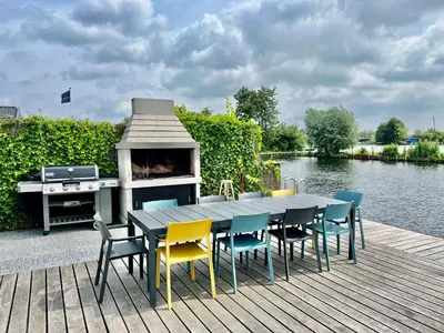 a table and chairs and a grill on a wooden deck at New - Waterfont Villa08 - Private Residence on a lake near Amsterdam in Vinkeveen