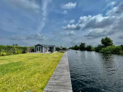 a house on the side of a river with a dock at New - Waterfont Villa08 - Private Residence on a lake near Amsterdam in Vinkeveen