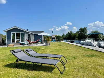 a bench sitting in the grass in front of a house at New - Waterfont Villa08 - Private Residence on a lake near Amsterdam in Vinkeveen
