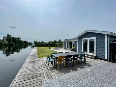 a house on a dock with a table and chairs at New - Waterfont Villa08 - Private Residence on a lake near Amsterdam in Vinkeveen