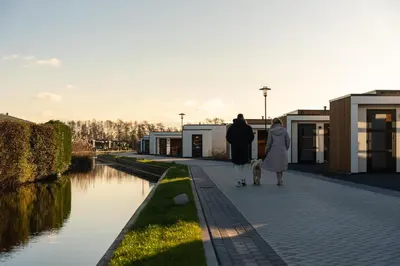 two people walking a dog next to a canal at MarinaPark Residentie Nieuw Loosdrecht in Loosdrecht