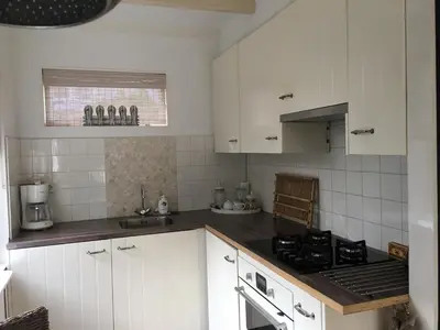 a kitchen with white cabinets and a stove top oven at Summerhouse Zandvoort in Zandvoort