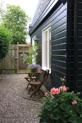a patio with a table and flowers next to a building at Summerhouse Zandvoort in Zandvoort