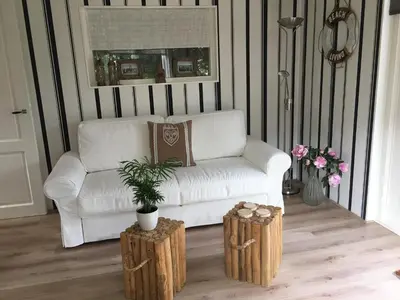 a living room with a white couch and two wooden stools at Summerhouse Zandvoort in Zandvoort