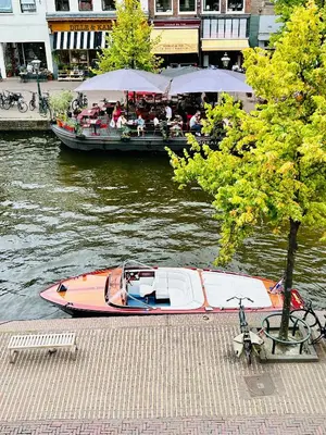 a boat is docked next to a restaurant on a river at Leiden City Centre Canal View or Terrace View Apartments in Leiden