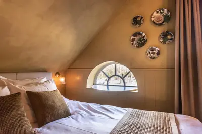 an attic bedroom with a bed and a window at The Butchersfarm in Ter Aar