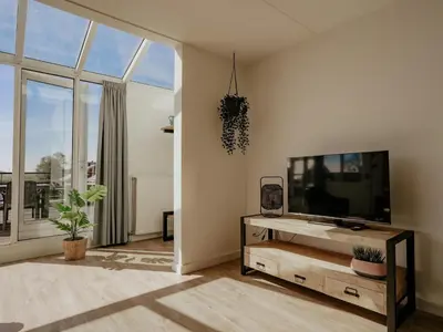 a living room with a tv and a large window at Apartment in Waterpark in Uitgeest in Uitgeest