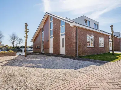 a brick house on a gravel driveway at Houseboat in Waterpark with Private Dock in Uitgeest
