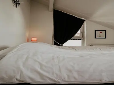 a white bed in a bedroom with a window at Houseboat in Waterpark with Private Dock in Uitgeest