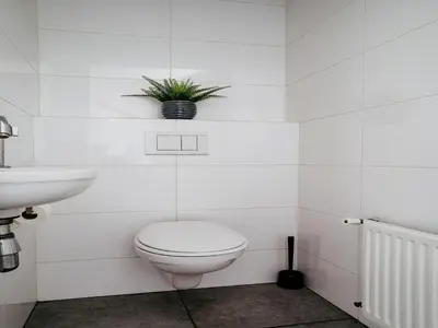 a white bathroom with a toilet and a sink at Houseboat in Waterpark with Private Dock in Uitgeest