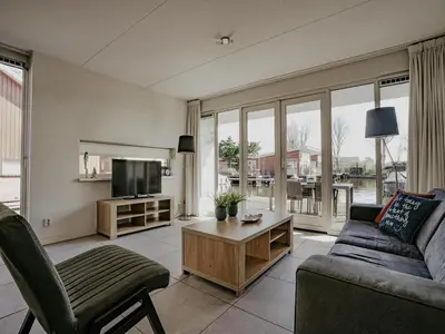 a living room with a couch and a tv at Houseboat in Waterpark with Private Dock in Uitgeest