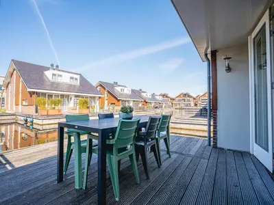 a table and chairs on a deck with a balcony at Apartment in Waterpark with Private Jetty in Uitgeest