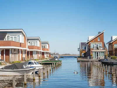 a group of boats docked next to houses on the water at Apartment in Waterpark with Private Jetty in Uitgeest
