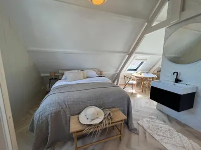 a bedroom with a bed and a sink and a table at Loft met zeezicht in Egmond aan Zee