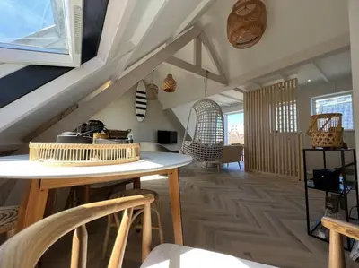 a living room with a table and some chairs at Loft met zeezicht in Egmond aan Zee