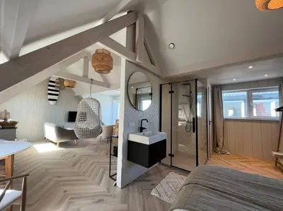 a bedroom with a bed and a bathroom with a sink at Loft met zeezicht in Egmond aan Zee