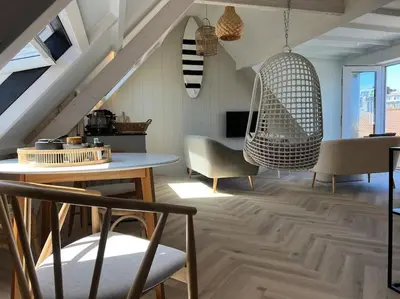 a living room with chairs and a table and swings at Loft met zeezicht in Egmond aan Zee
