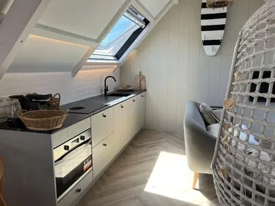 an attic kitchen with a sink and a stove at Loft met zeezicht in Egmond aan Zee